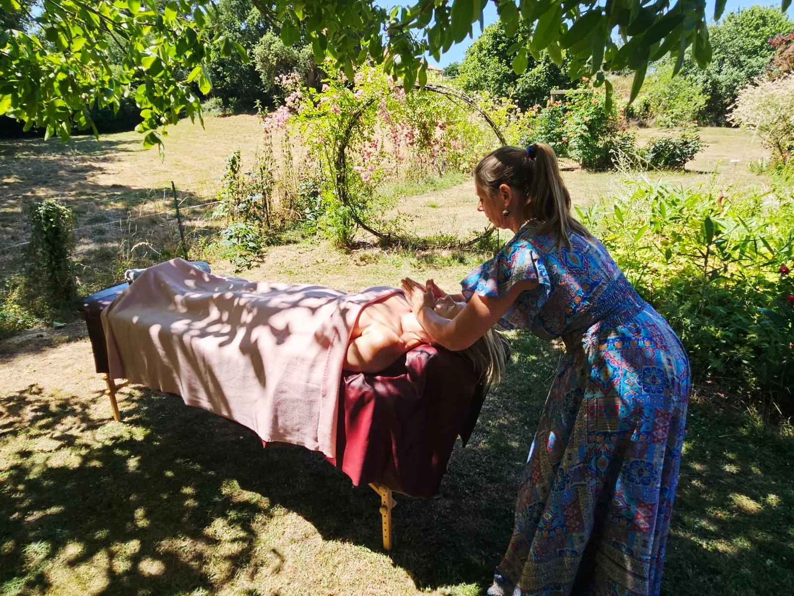 Séverine masse la tête d’une personne allongée dans un jardin