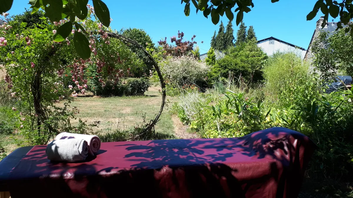 Espace de soin au jardin d’Elfenn Ayurvéda, sous une arche fleurie